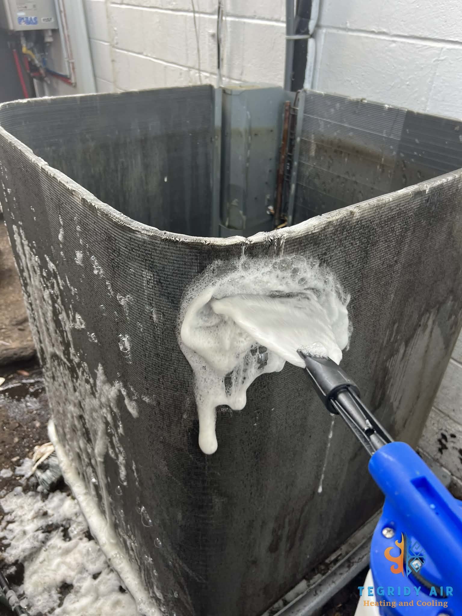 AC technician cleaning condenser coils on outdoor unit in Kenner Louisiana
